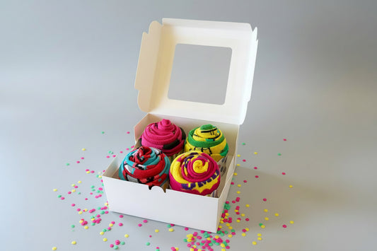 Colorful sock cupcakes in a white box with sprinkles on a gray background