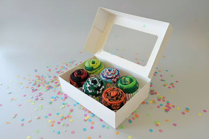 Box of 6 sports themed colorful cupcake socks with a clear window on a dark surface