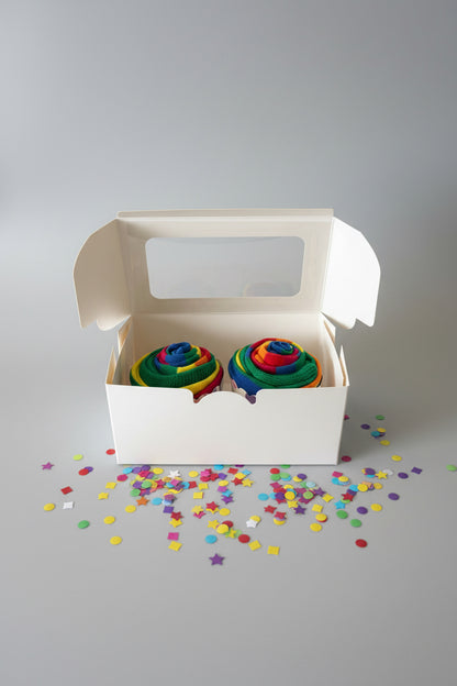 Two rainbow-colored cupcakes in a white box