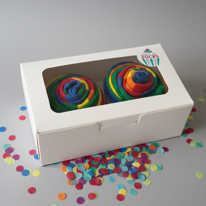 Colorful cupcake socks in a white box with a brand logo on a reflective surface.