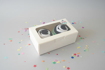Two pairs of cupcake socks in a box with a visible brand logo on a dark background
