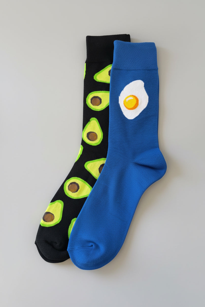 Two socks with avocado and egg designs on a dark background